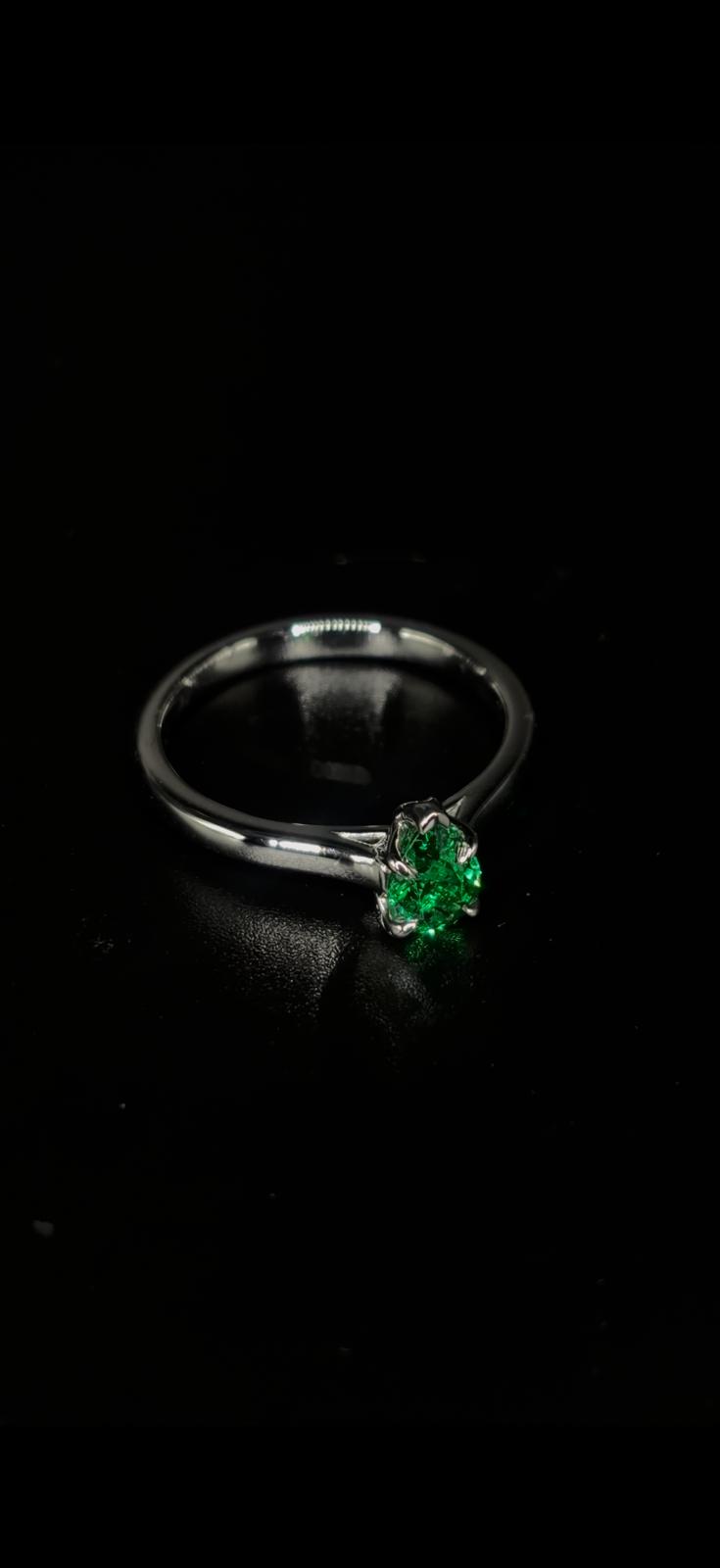 A pear-shaped emerald in a delicate claw setting on a platinum band.