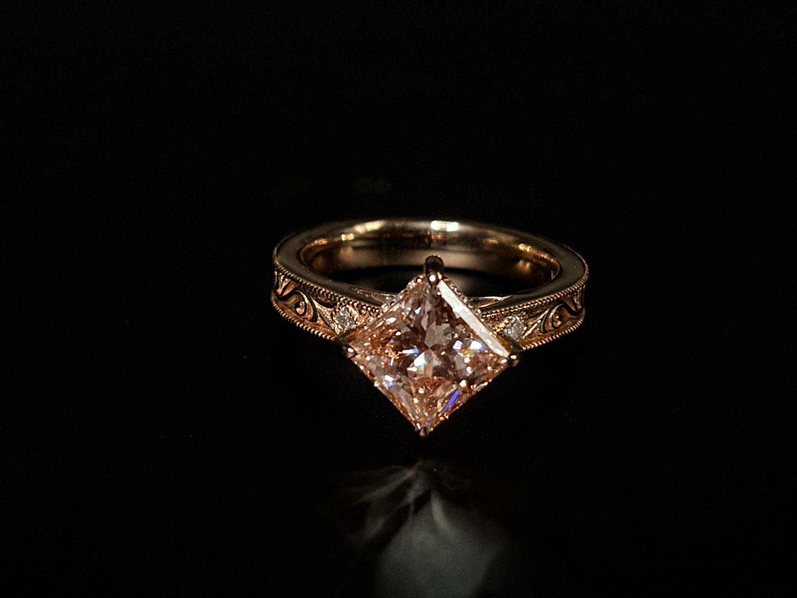 A pink centre stone framed by an ornate rose gold band.